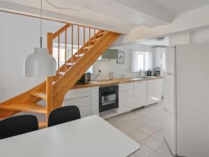 a kitchen with white cabinets and a wooden staircase at Apartment Sylviane - 500m from the sea by Interhome in Gudhjem