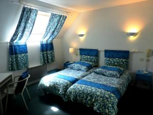 a bedroom with a bed with blue sheets and a window at Hotel Restaurant Aux Sapins in Thann