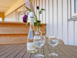 two wine glasses and a bottle and a vase with flowers at Apartment Gulla - 300m from the sea by Interhome in Gudhjem