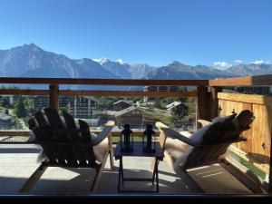 two chairs and a table on a balcony with mountains at Grimpeur 9 ski in-out, Spa Access in Nendaz