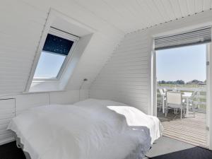 a white bedroom with a bed and a balcony at Holiday Home Nilia - 3-5km from the sea by Interhome in Østermarie