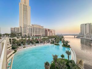 a large swimming pool next to a river with buildings at FIRST CLAS 1BR Creek Beach , Lagoon Access in Dubai
