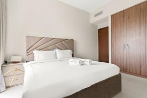 a bedroom with a large white bed with two towels at FIRST CLAS 1BR Creek Beach , Lagoon Access in Dubai +27 photos