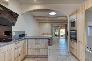 a kitchen with wooden cabinets and a tile floor at Villa Piscine proche Lac du Salagou in Saint-Guiraud