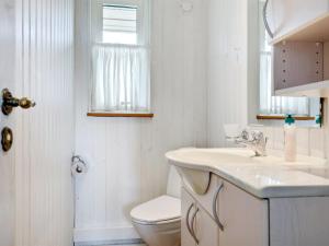 a white bathroom with a toilet and a sink at Holiday Home Voitto - 150m from the sea by Interhome in Allinge