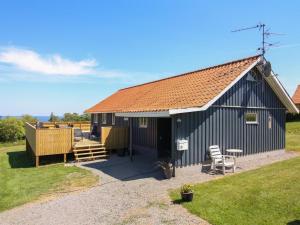 a black building with a table and a chair in front at Holiday Home Voitto - 150m from the sea by Interhome in Allinge