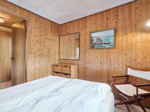 a bedroom with wooden walls and a bed and a chair at Holiday Home Joske - 250m from the sea by Interhome in Hasle +16 photos