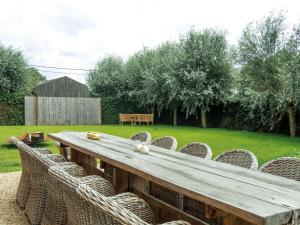 a wooden table with wicker chairs in a yard at Holiday Home in Moorslede with Pool and Jacuzzi in Moorslede