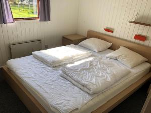 un grande letto con lenzuola bianche e cuscini sopra di Holiday Home Harald - 300m from the sea by Interhome a Bøtø By
