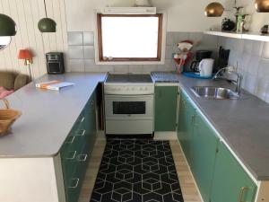 una cucina con mobili verdi, un lavello e una stufa di Holiday Home Harald - 300m from the sea by Interhome a Bøtø By