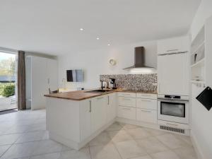 a kitchen with white cabinets and a stove top oven at Apartment Aamunde - 100m from the sea by Interhome in Marielyst