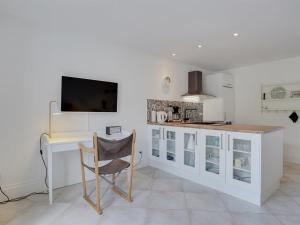 a white kitchen with a desk and a tv at Apartment Aamunde - 100m from the sea by Interhome in Marielyst +4 photos