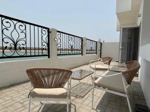 a patio with chairs and tables on a balcony at Beach Front 03 bedroom villa plus maid room in Al Ḩamrīyah