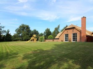 un grande cortile con un parco giochi e un edificio in mattoni di Holiday Home Erra - 250m from the sea by Interhome a Bøtø By