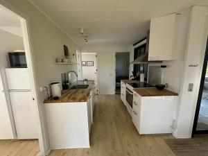 a kitchen with white cabinets and a wooden floor at Holiday Home Ady - 150m from the sea by Interhome in Augustenborg