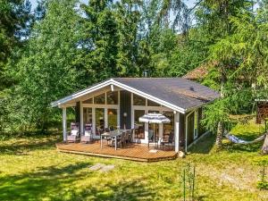 a house with a deck with chairs and an umbrella at Holiday Home Hertta - 200m from the sea by Interhome in Marielyst