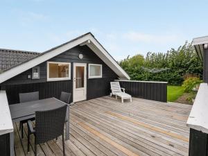 a wooden deck with a table and chairs on it at Holiday Home Sella - 500m from the sea by Interhome in Neder Lysabild