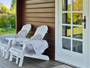 zwei weiße Stühle auf einer Veranda mit einer Tür in der Unterkunft Holiday Home Swartebrand - 450m from the sea by Interhome in Neder Lysabild