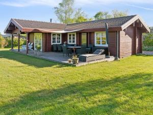 ein kleines Haus mit einer Terrasse mit Tisch und Stühlen in der Unterkunft Holiday Home Swartebrand - 450m from the sea by Interhome in Neder Lysabild