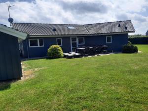 a blue house with a picnic table in the yard at Holiday Home Toja - 700m from the sea by Interhome in Neder Lysabild
