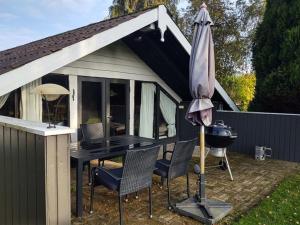 a patio with a grill and an umbrella and chairs at Holiday Home Rieke - 300m from the sea by Interhome in Skovmose