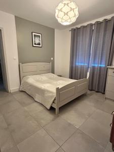 a bedroom with a bed and a chandelier at Appartement 40 m2 avec parking et petite terrasse in Montfaucon