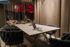 a table with a laptop on it in a room with chairs at Aquila Grand Suites - Noida Sector 136 in Noida +85 photos