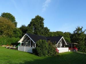 a white house with a black roof on a green field at Holiday Home Aulis - 230m from the sea by Interhome in Sarup