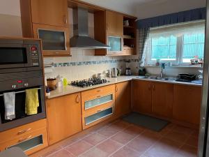 a kitchen with wooden cabinets and a stove top oven at Vivenda espaçosa com jardim e churrasqueira in Alcabideche