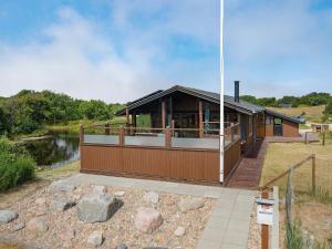 a house with a large deck next to a river at Holiday Home Frigga - 400m from the sea by Interhome in Fanø