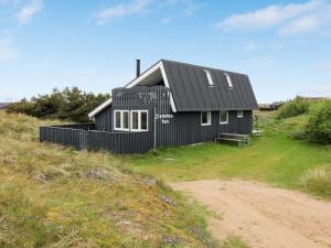 a black house sitting on top of a hill at Holiday Home Casandra - 600m from the sea by Interhome in Fanø +17 photos