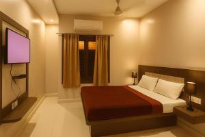 a bedroom with a bed and a tv and a window at HOTEL SWARGADWAR GOLDEN SEA BEACH Near Bengali Market with Prime Location - Home town Inn & Suits - Best Hotel In Puri in Puri
