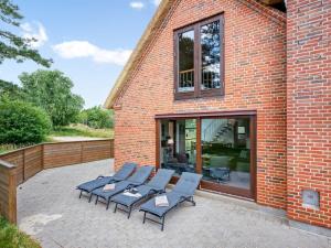 a patio with four lounge chairs and a brick building at Holiday Home Martje - 900m from the sea by Interhome in Fanø