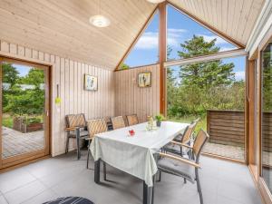 a dining room with a table and chairs and windows at Holiday Home Martje - 900m from the sea by Interhome in Fanø +22 photos