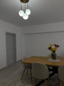 un tavolo da pranzo con sedie e un vaso di fiori di Vanex a Petricani Altre 5 foto
