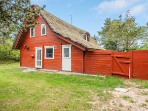 a red house with a thatched roof and a fence at Holiday Home Tine - 2-3km from the sea by Interhome in Vesterhede