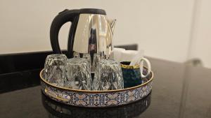 a tea pot with glasses in a holder on a counter at Skyline Hotel in Sargodha