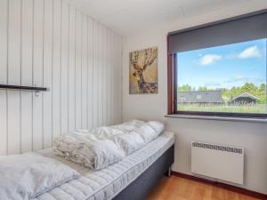 un lit dans une chambre avec une grande fenêtre dans l'établissement Holiday Home Halfdan - 1-1km from the sea by Interhome, à Mølby