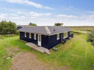 a black house with a porch on a grass field at Holiday Home Swana - 550m from the sea by Interhome in Lakolk