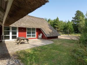 a red cabin with a picnic table and a bench at Holiday Home Jenna - 1-4km from the sea by Interhome in Vesterhede