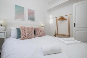 - une chambre blanche avec un lit blanc et des oreillers dans l'établissement Beautiful Mews Cottage near Brighton Seafront in Rottingdean Village, à Rottingdean