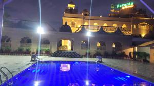 a swimming pool in front of a building at night at Revanta Suites in Vasai