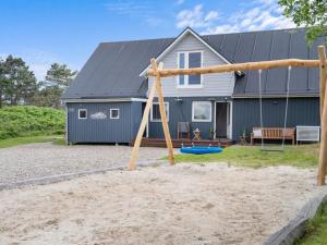 a playground in front of a house at Holiday Home Taio - 500m from the sea by Interhome in Lakolk