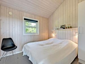 a bedroom with a white bed and a black chair at Holiday Home Chrisse - 550m from the sea by Interhome in Lakolk
