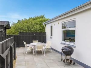 eine Terrasse mit einem Tisch, Stühlen und einem Grill in der Unterkunft Holiday Home Pupa - 500m from the sea by Interhome in Lakolk