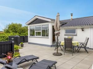 eine Terrasse mit Tisch und Stühlen und einem Sonnenschirm in der Unterkunft Holiday Home Pupa - 500m from the sea by Interhome in Lakolk