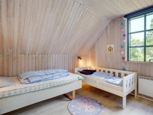 two beds in a room with a wooden wall at Holiday Home Benedikta - 2-4km from the sea by Interhome in Vesterhede