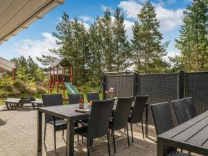 une terrasse avec une table et des chaises ainsi qu'une aire de jeux dans l'établissement Holiday Home Livni - 3-8km from the sea by Interhome, à Tagholm
