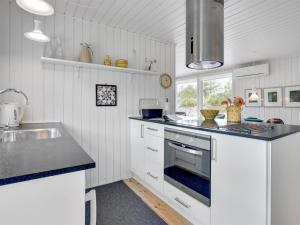 une cuisine blanche avec un évier et une cuisinière four supérieur dans l'établissement Holiday Home Fredrikka - 3-9km from the sea by Interhome, à Tagholm