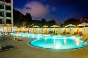 ein Swimmingpool mit Stühlen und Sonnenschirmen in der Nacht in der Unterkunft Luxury Studio B02 SB in Sonnenstrand